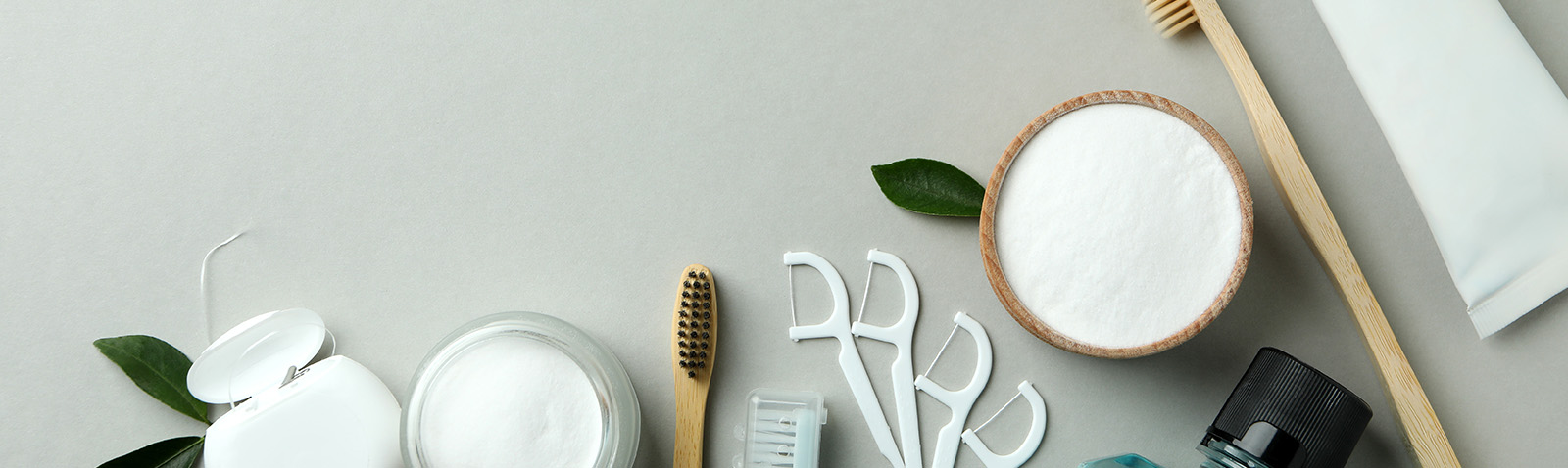 The image shows a collection of items on a table, including various beauty products, toothbrushes, and bowls, with a focus on skincare and dental hygiene items.