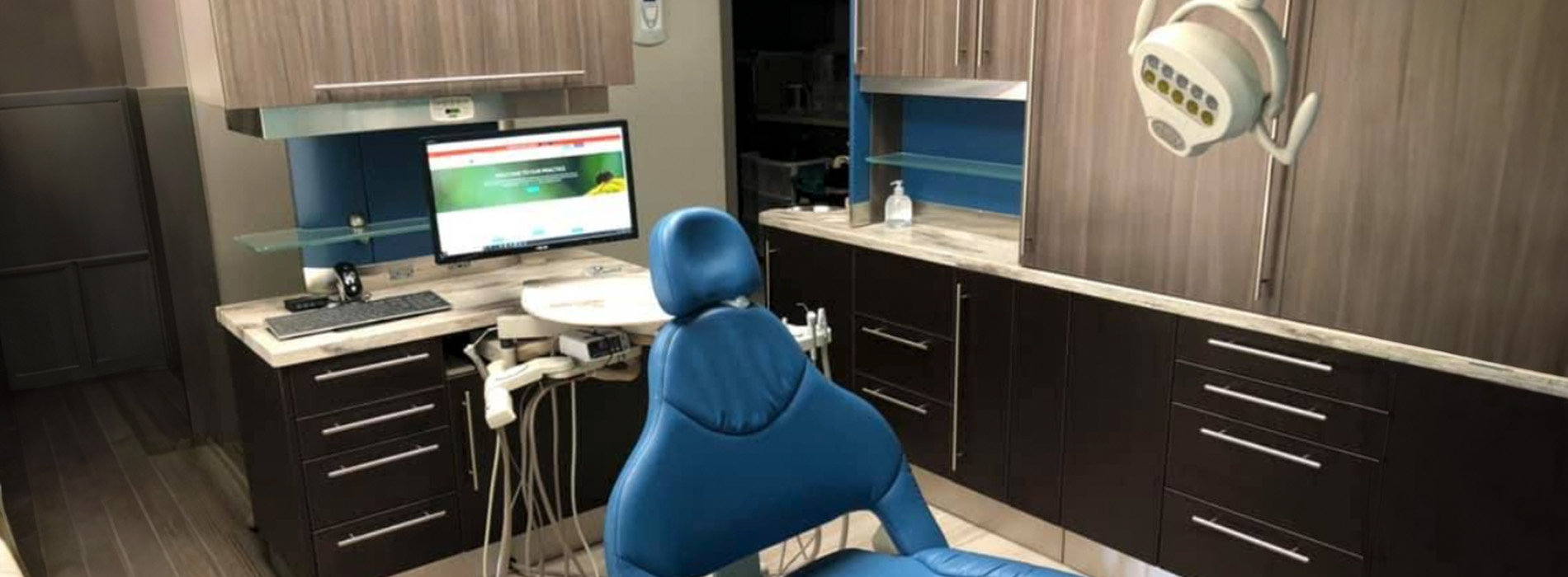 The image depicts an interior space with a person sitting at a desk using a computer, surrounded by kitchen cabinets and appliances, with a cartoonish blue character on the desk.