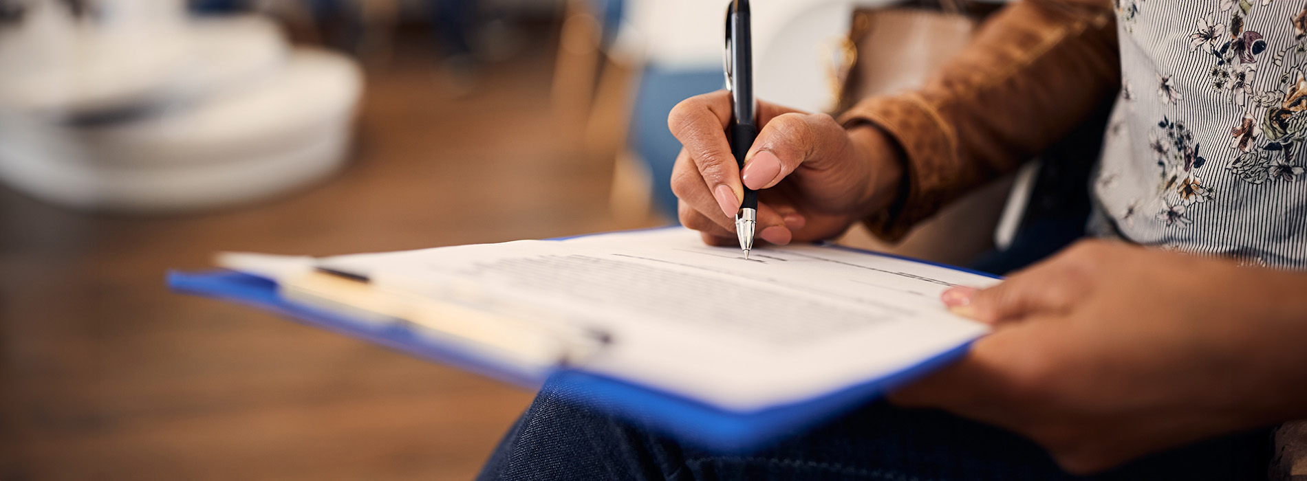 The image shows a person writing on a clipboard with various papers around them, suggesting an organizational or administrative task.