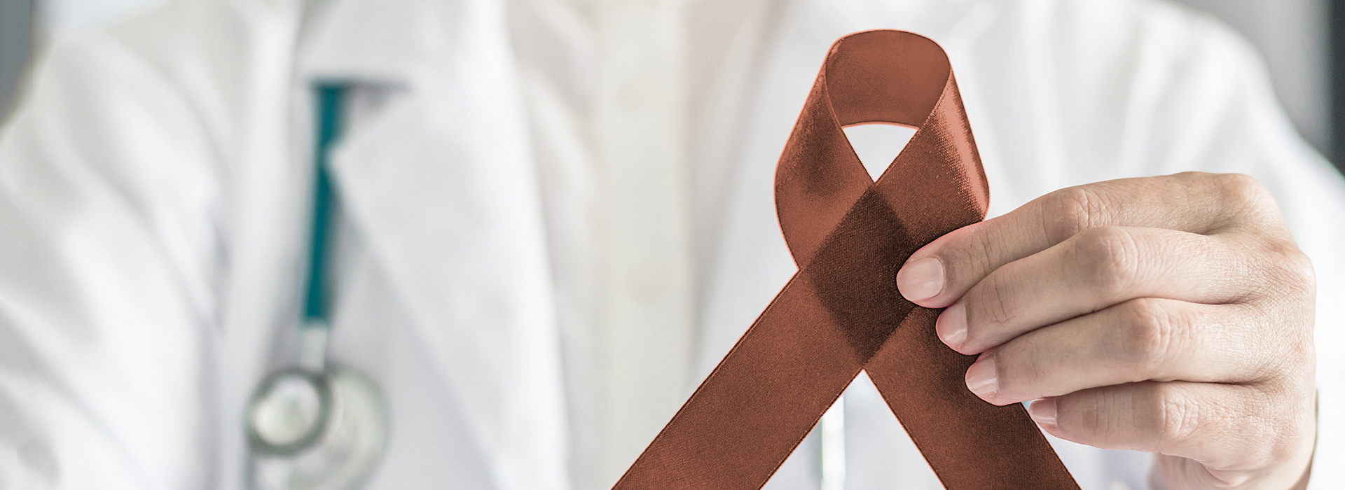 The image features a medical professional holding a red ribbon with an A symbol in their hand, set against a blurred background that suggests a hospital environment.